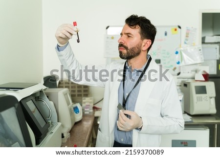 Smart biochemist or pathologist checking a test tube with a blood sample to make medical tests