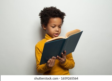 Smart black child boy reading a book on white background