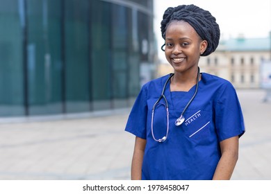 Smart Black Girl Medical Student, Happy Young African American Woman Doctor, Nurse In Blue Uniform, Stethoscope, Smiling Afro Female At University, College, Hospital, Clinic Outdoor. Copy Space