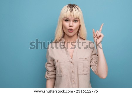 smart blond young woman shows her hand towards the wall