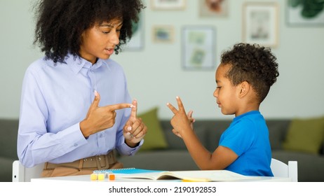 A smart boy counts on his fingers, studies with a private teacher in the office, a child learns numbers and how to count, sits at a table with a tutor - Shutterstock ID 2190192853