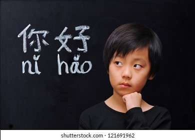 Smart boy in front of blackboard with Chinese words for "hello"