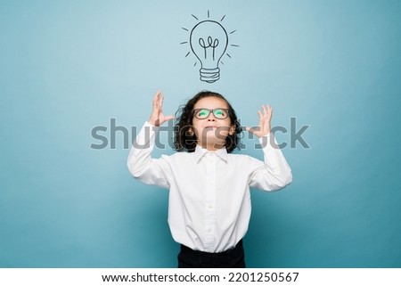 Smart boy having a clever idea while playing businessman and using his imagination against a background with a lightbulb graphic