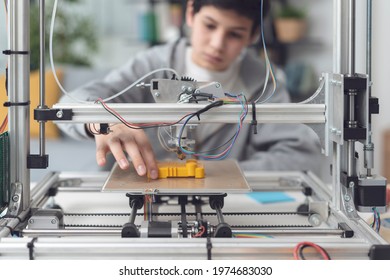 Smart boy printing a prototype using a 3D printer, science and technology concept