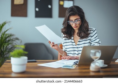 A smart business woman who keeps a paper account using a calculator, an old woman manages the account's finances, calculates the tax on the cash budget, plans to pay off a bank loan debt - Powered by Shutterstock