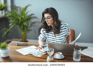 A smart business woman who keeps a paper account using a calculator, an old woman manages the account's finances, calculates the tax on the cash budget, plans to pay off a bank loan debt - Powered by Shutterstock