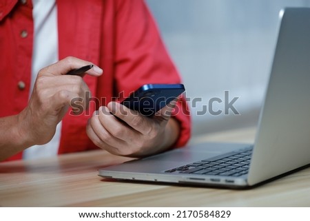 smart businessman with red shirt and working with laptop smartphone while working on his project