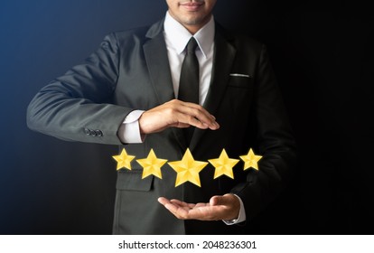 A smart bussinessman in suit is holding  a screen five gold stars (5) rating, Customer service experience and business satisfaction survey,  Feedback, review and rating concepts.tif