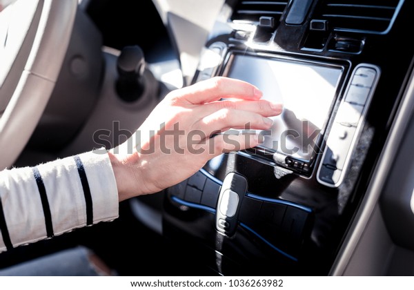 Smart car.\
Young careful occupied woman touching to the cars computer setting\
up control panel being in the\
car.