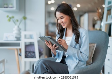 smart casual asian female startup entrepreneur small business owner business woman smile hand use tablet working organize inventory products shelf checking in showroom studio office daytime background