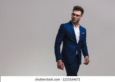 Smart Casual Man Walks And Looks Back Over His Shoulder On Grey Background