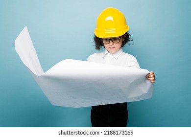 Smart caucasian boy reading the blueprints or construction plans while dreaming to become an architect 