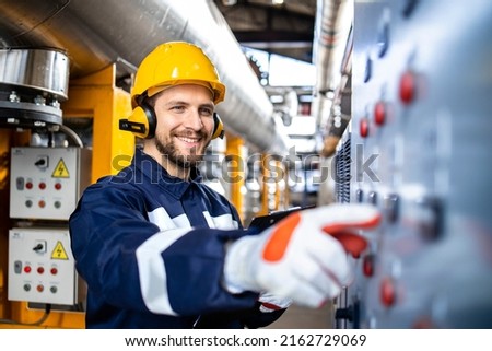 Smart caucasian factory worker wearing hardhat, earmuffs and working in power plant.