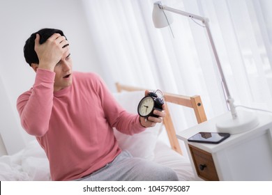 smart caucasian man iw wakeup late  on bed with black alarm clock in white room background