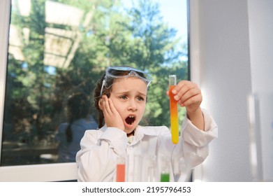 Smart Caucasian schoolgirl watching fascinating wonderful chemical reaction, between multi-colored chemicals and reagents, taking place in a test tube that she holds in her hands at a chemistry - Powered by Shutterstock