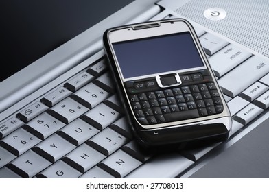 Smart Cell Phone On A Silver Laptop