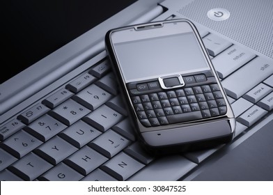 Smart Cell Phone On A Silver Laptop