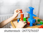 smart child, schoolboy playing with educational toy, wooden geometric figures, blocks in boy