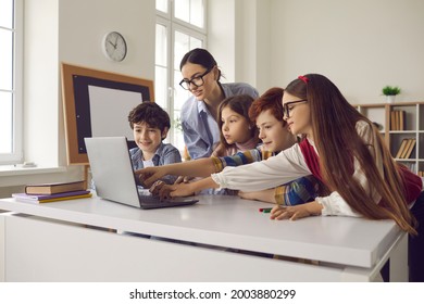 Smart children pupil pointing at laptop screen while discussing media material or online project with teacher on lesson in school classroom. Curious diverse elementary students and female educator - Powered by Shutterstock