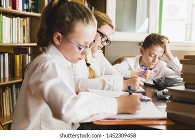 Smart children writing sitting in library 