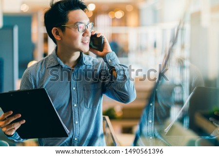 smart confidence asian startup entrepreneur business owner businessman smile hand use smartphone woking in office background