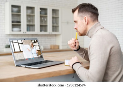 Smart confident guy is studying online, watching online webinar on the laptop and takes notes, a female tutor with a flip chart on the screen. E-learning concept