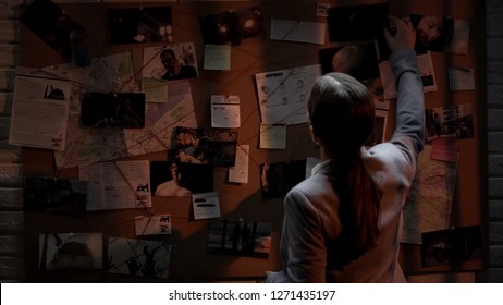 Smart detective looking attentively at investigation board, evaluating clues - Shutterstock ID 1271435197