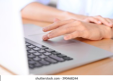 Smart device.  Selective focus of finger of nice  woman touching touchpad and working on the laptop
