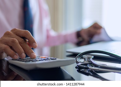 Smart Doctor Hand Using Calculator For Account About Medical Costs With Stethoscope And Computer Notebook On The Desk At Modern Office,clinic Or Hospital. Healthcare Costs And Fees Conceptual.