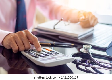 Smart Doctor Hand Using Calculator For Calculate About Medical Costs With Stethoscope And Computer Notebook On The Desk At Modern Office At Clinic Or Hospital.Medical Healthcare Costs And Fees Concept