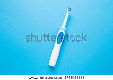 Smart electric toothbrush on a blue isolated background.