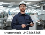 Smart employee. Factory worker is indoors with hard hat.