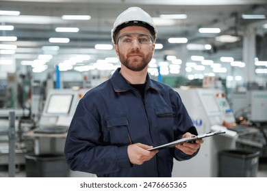 Smart employee. Factory worker is indoors with hard hat. - Powered by Shutterstock