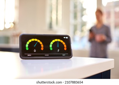 Smart Energy Meter In Kitchen Measuring Domestic Electricity And Gas Use With Figure In Background