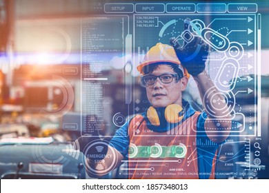 Smart engineer worker using advance technology visual holographic air screen to program and control robotic arm for automated production in modern future factory.