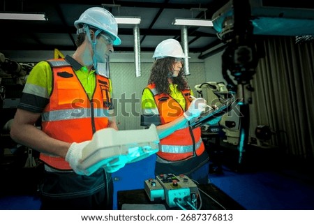 In a smart factory, an engineer uses an augmented reality tablet to guide her partner through a complex repair, overlaying digital instructions on the robot after an AI alert.