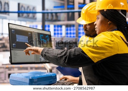 Smart factory technicians utilizing computer to enhance solar energy efficiency in industrial plant. Industry 4.0 experts supervise automated machinery involved in solar panel production.