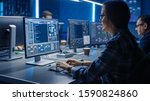 Smart Female IT Programer Working on Desktop Computer in Data Center System Control Room. Team of Young Professionals Doing Code Programming