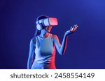 Smart Female standing surrounded by neon light wear VR headset connecting metaverse, futuristic cyberspace community technology. Elegant woman use hand holding generated virtual object. Hallucination.