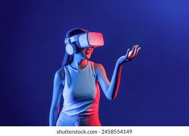 Smart Female standing surrounded by neon light wear VR headset connecting metaverse, futuristic cyberspace community technology. Elegant woman use hand holding generated virtual object. Hallucination. - Powered by Shutterstock