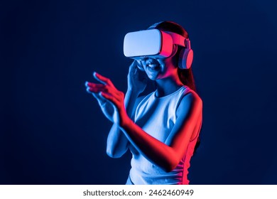 Smart female standing with surrounded by cyberpunk neon light wear VR headset connecting metaverse, futuristic cyberspace community technology. Woman using hand touching virtual object. Hallucination. - Powered by Shutterstock