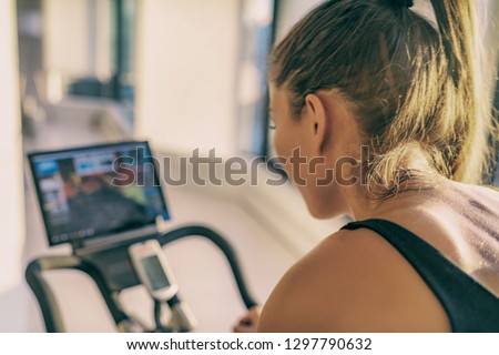 Smart fitness home workout biking screen with online classes woman training on stationary bike equipment indoors for biking exercise. Indoor cycling. Focus on the sweat on person's back. Stock photo © 