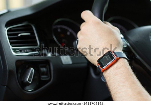 Smart fitness watch on young\
males wrist whilst driving in the car. Modern technology concept.\
