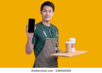 Smart Friendly Asian Male Glasses Barista Small Coffee Shop Owner In Apron Hand Gesture Welcome Customer Come And Enjoy His Coffee Drink,happy Asia Man Show Smartphone Online Order Is Ready For You