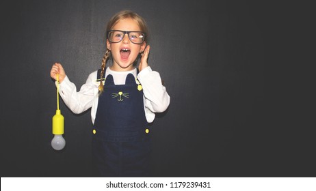 Smart Girl With Light Bulb In Classroom. Success, Idea And Creative Concept. Back To School.