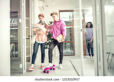 Smart girlfriend. Stylish boyfriend standing on purple skate listening to smart beautiful girlfriend - Powered by Shutterstock