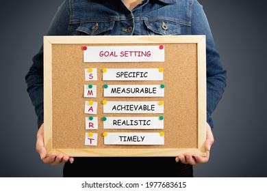 Smart Goal Setting Idea On A Pinboard In The Hand Of A Woman Person Wearing A Denim Shirt On A Gradient Blue Background With A Clipping Path. 