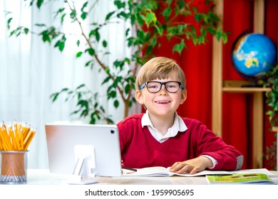 Smart Happy Preteen Boy Boy With Eye Blue Light Blocking Glasses While Using Computer Laptop And Notebook Studying Online Lessons. Work At Home Remotely Doing Homework. Kid In Uniform.
