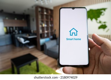 Smart Home App On Smartphone. Remote Control Of Electronic Devices In Apartment. Concept Of Controlling Smart Electronics In The House. Internet Of Things. All The Graphics On The Screen Are Made Up.