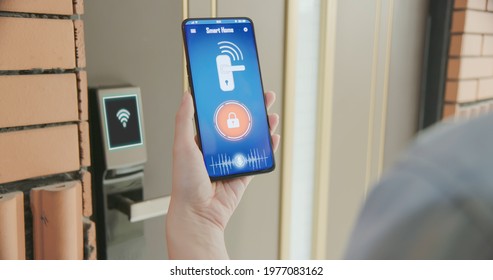 Smart home concept - close up of asian woman using voice assistant on cellphone to open electronic lock